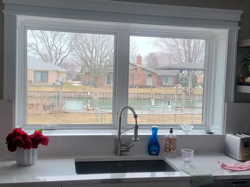 A kitchen with a sink and a window with a view of a lake.