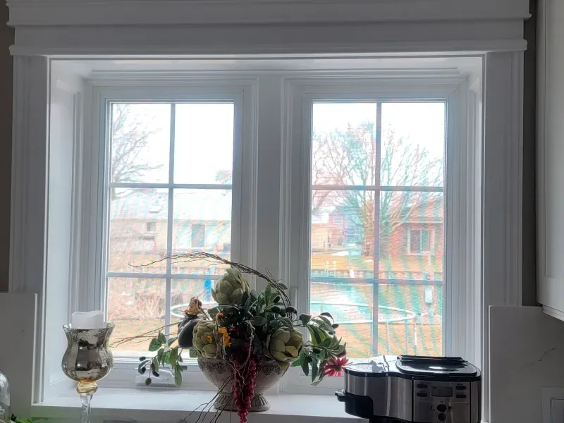 There is a vase of flowers on the window sill in the kitchen.