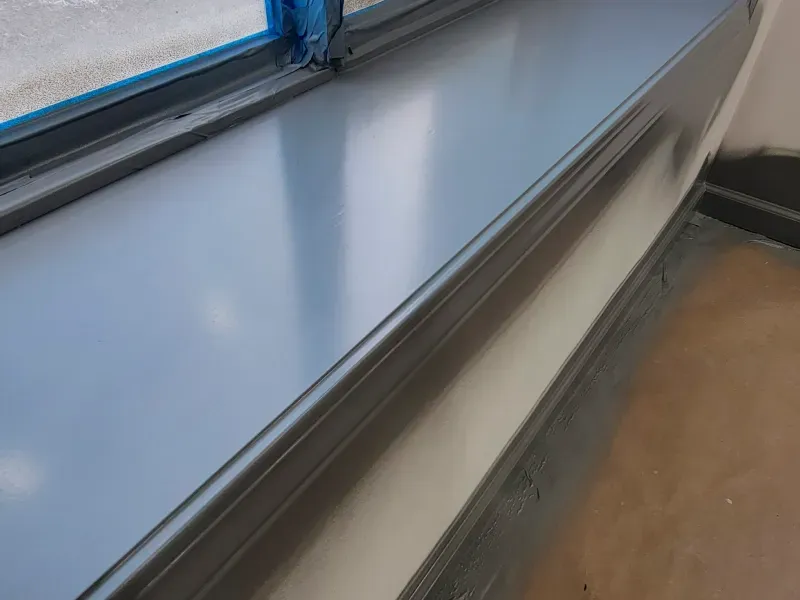 A close up of a window sill with blue tape on it.