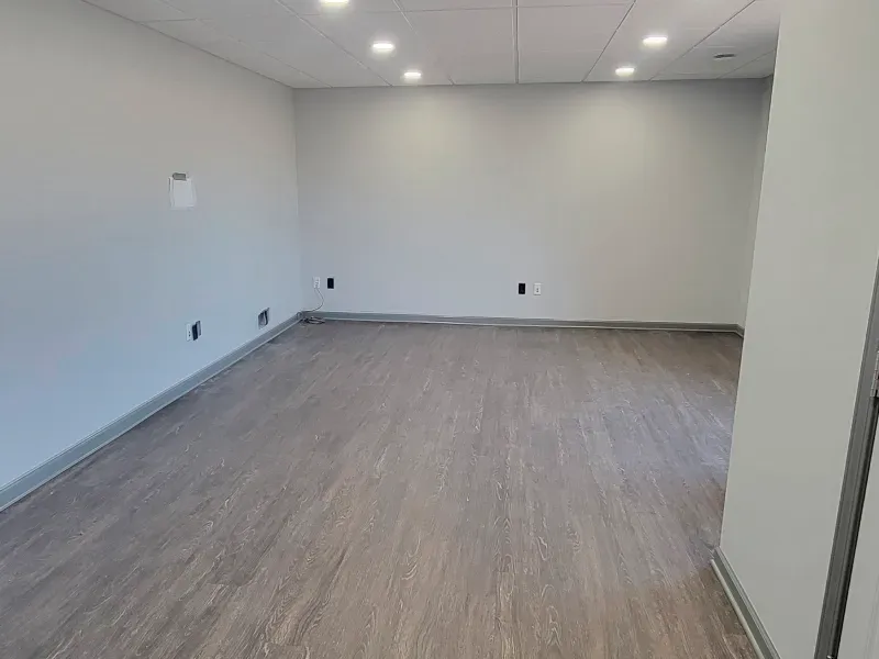An empty room with a wooden floor and white walls.