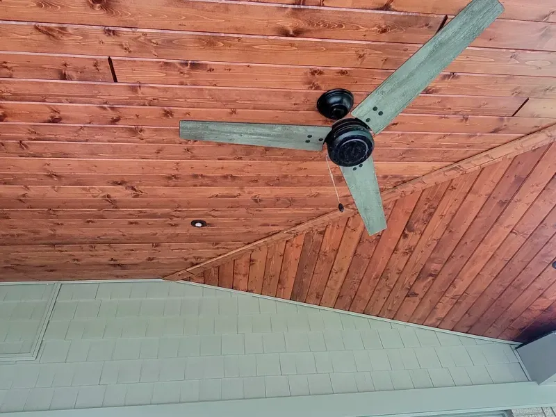 A ceiling fan is hanging from the ceiling of a wooden room.