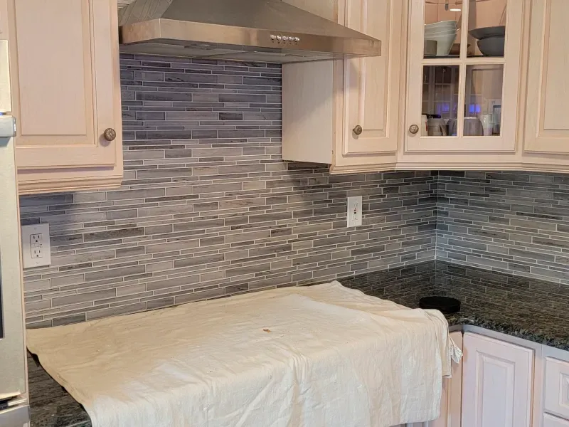 A kitchen with white cabinets and a stainless steel hood.
