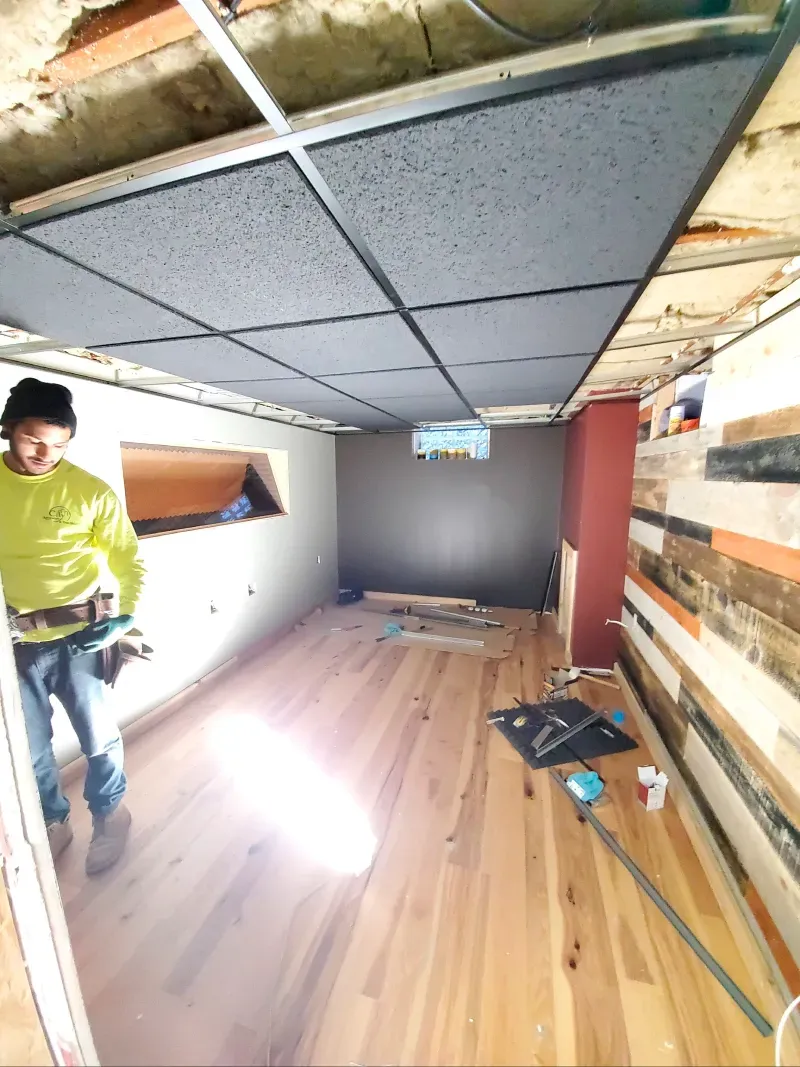 A man is standing in a room with a wooden floor.