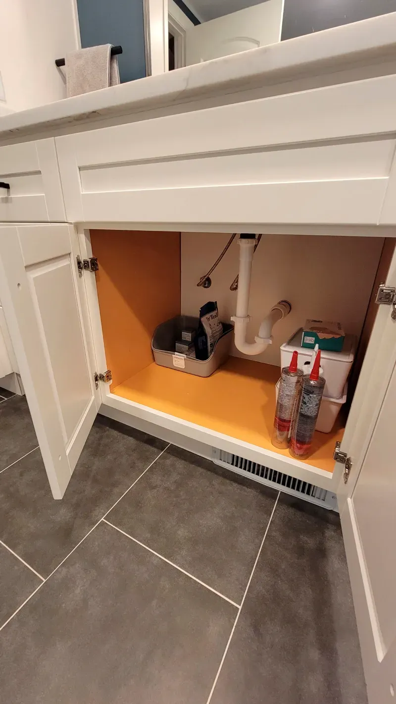 A bathroom vanity with the door open and a sink underneath it.