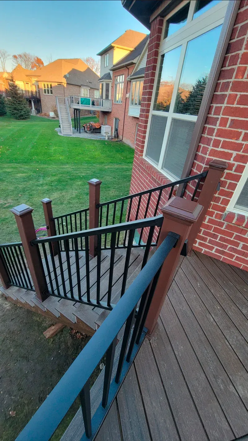 A wooden deck with stairs leading up to a brick house.
