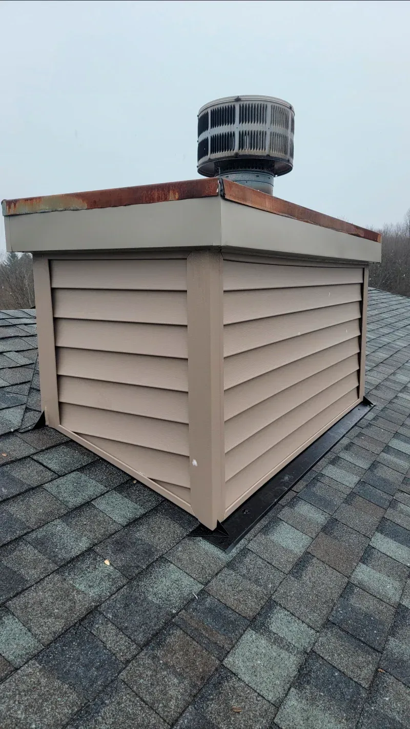 A chimney on top of a roof with siding on it.