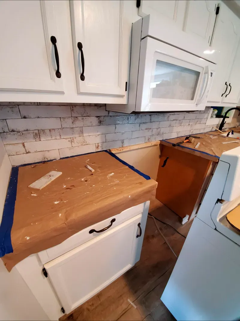A kitchen with white cabinets and a microwave.