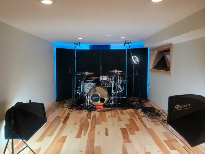 A drum set is sitting on a wooden floor in a room.
