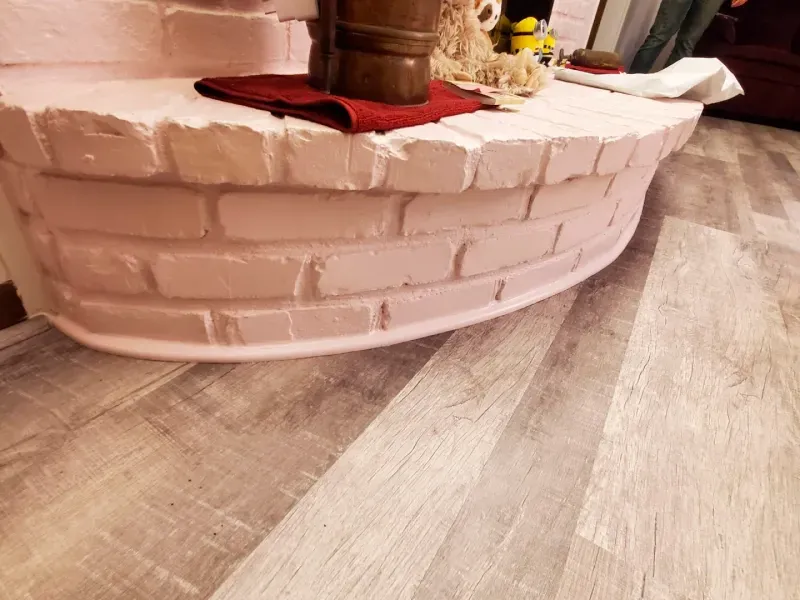 A brick fireplace is sitting on a wooden floor.