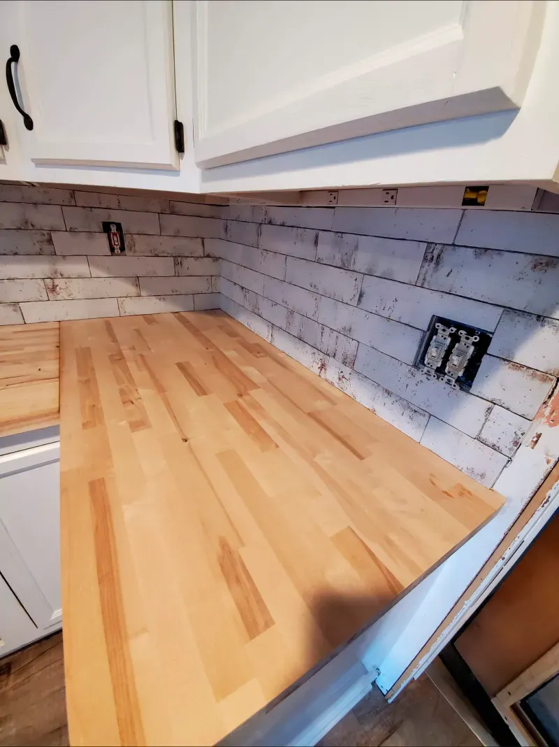 A kitchen with a wooden counter top and white cabinets