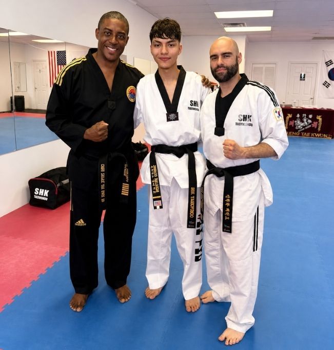 Two people practicing Brazilian Jiu-Jitsu on a mat; one in a black gi, one in a white gi, grappling.
