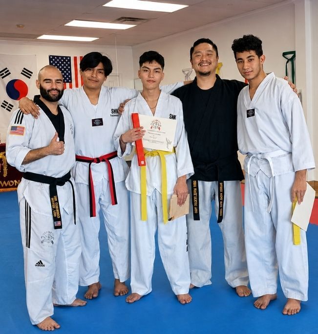 People practicing jiu-jitsu on mats, wearing gis in blue, black, and gray. Active grappling, gym setting.