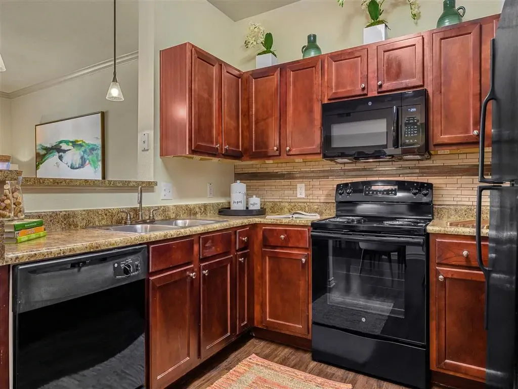 Modern kitchen with dark wood cabinets, granite countertops, stainless steel appliances, and a backsplash.