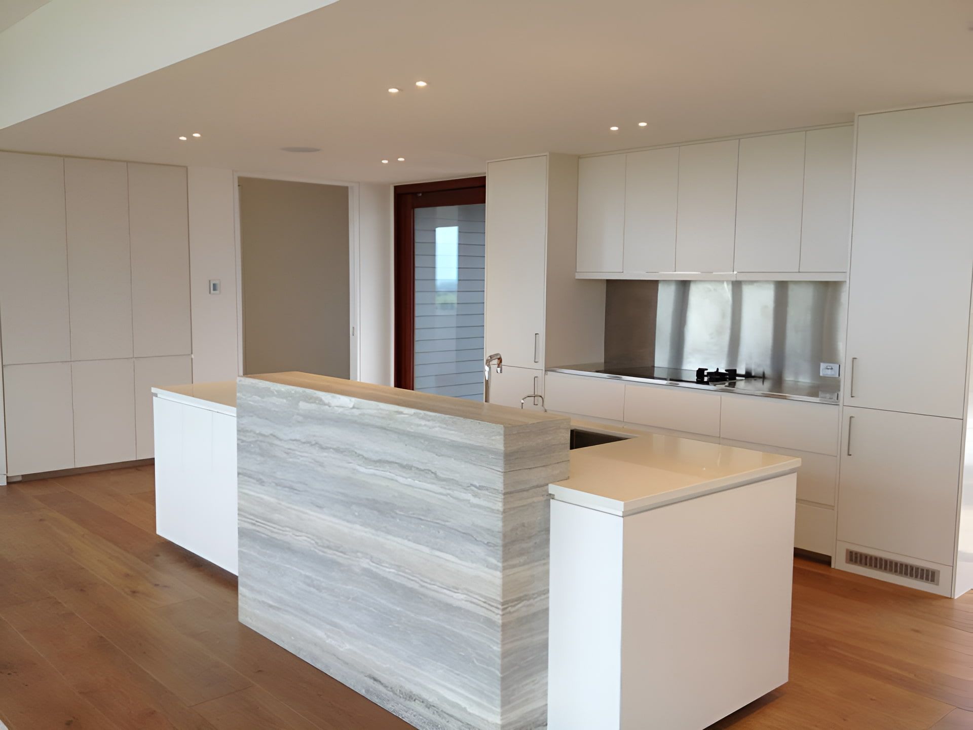 A Kitchen With White Cabinets And A Large Island In The Middle — North Coast Cabinets In Byron Bay, NSW