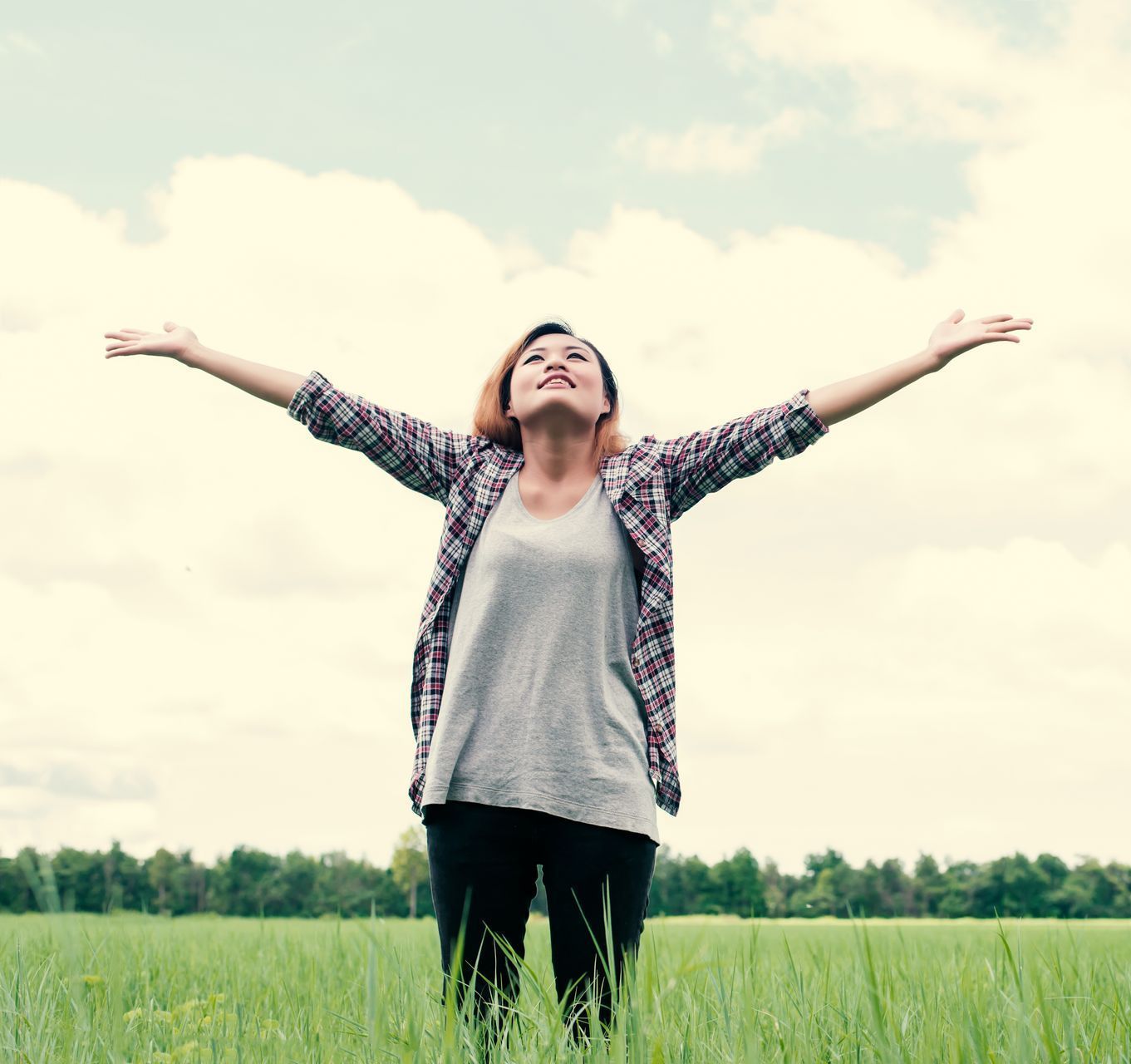 A woman is standing in a field with her arms outstretched