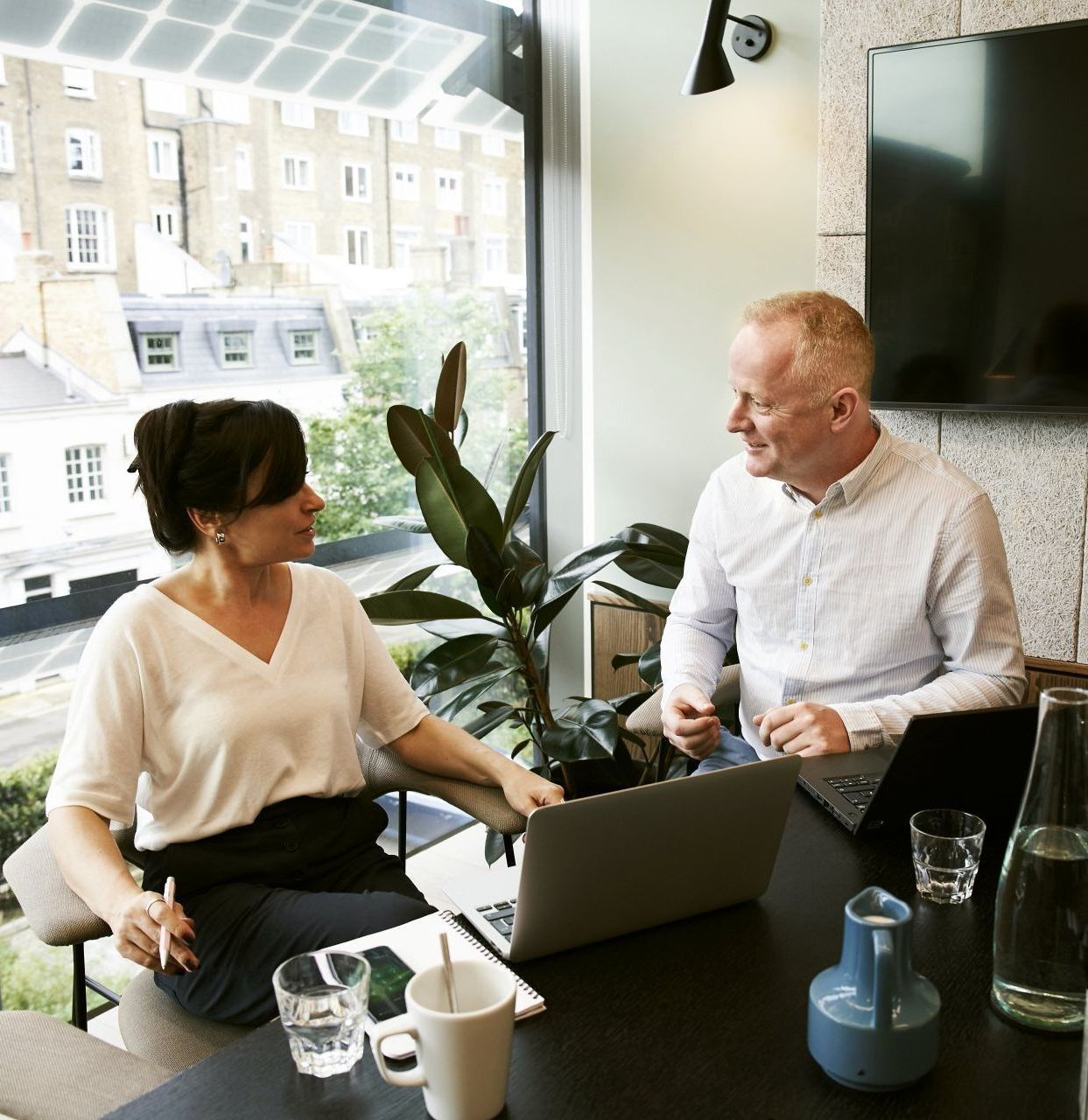 A man and a woman are sitting at a table with a laptop