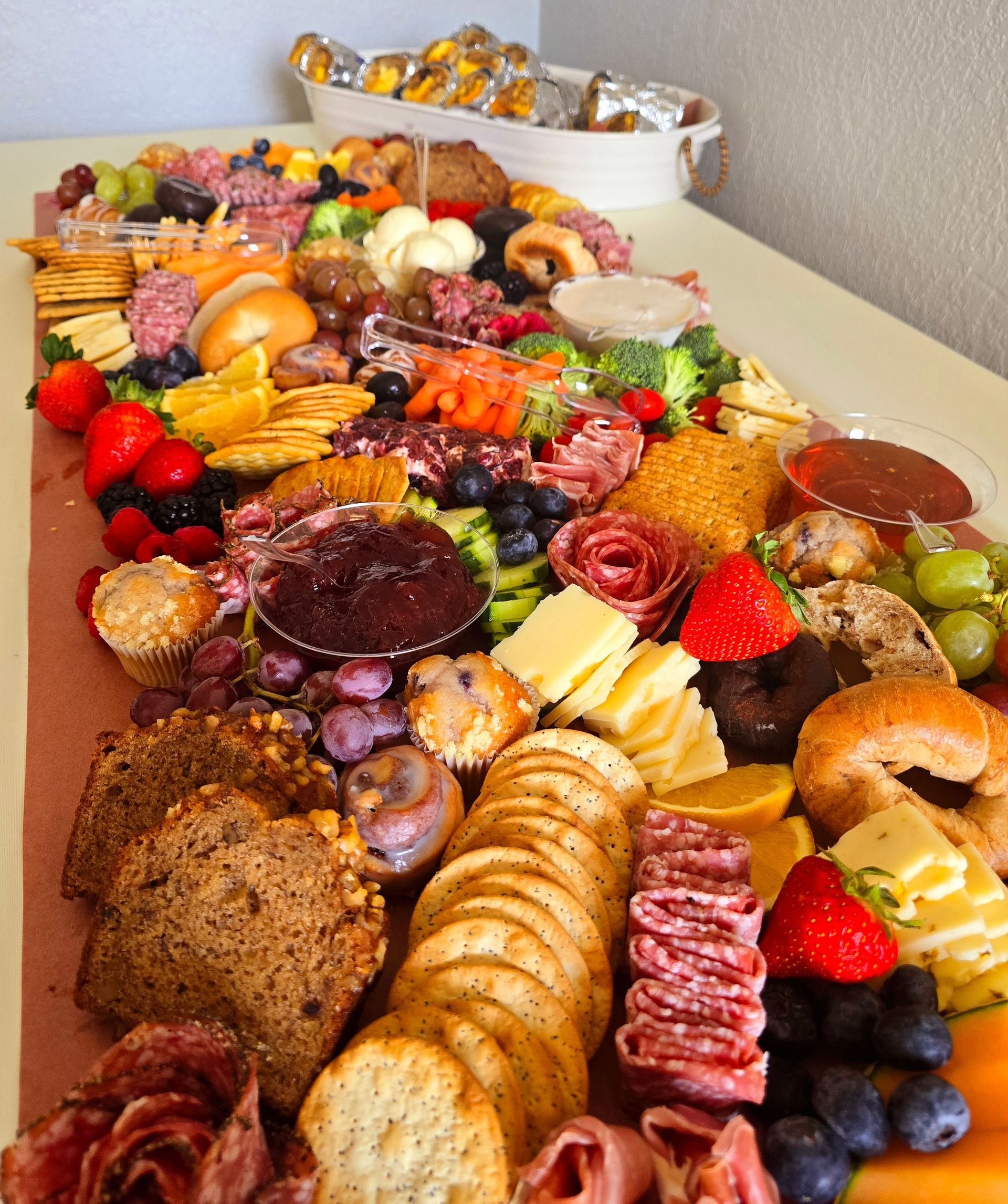 Charcuterie board overflowing with food: cheese, crackers, fruit, meats, and jam.