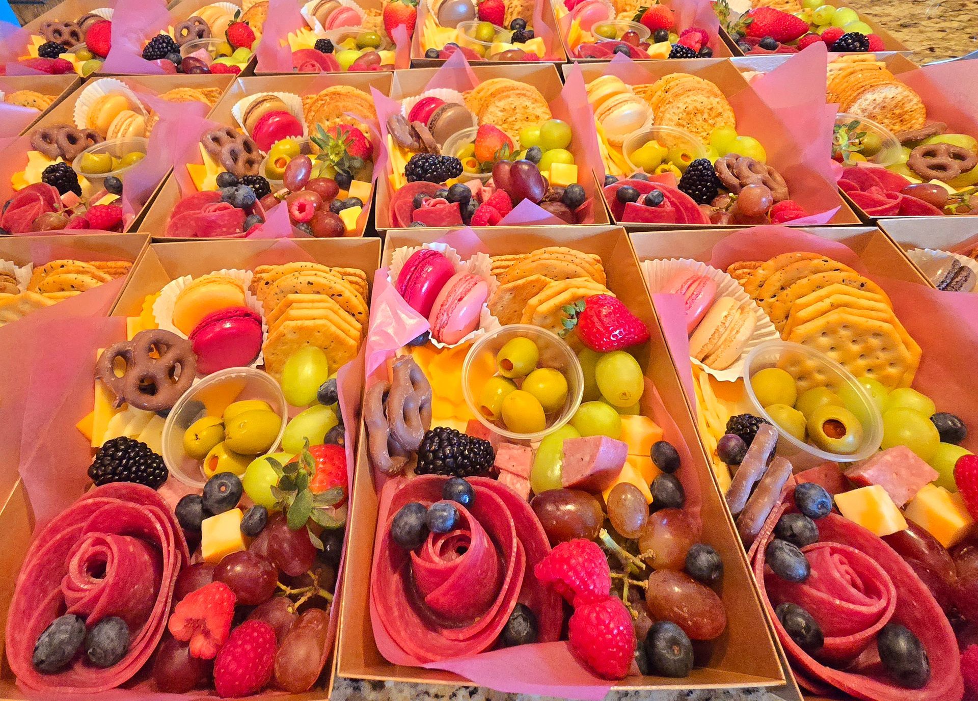 Charcuterie boards with fruit, crackers, and cheese, arranged in individual boxes.
