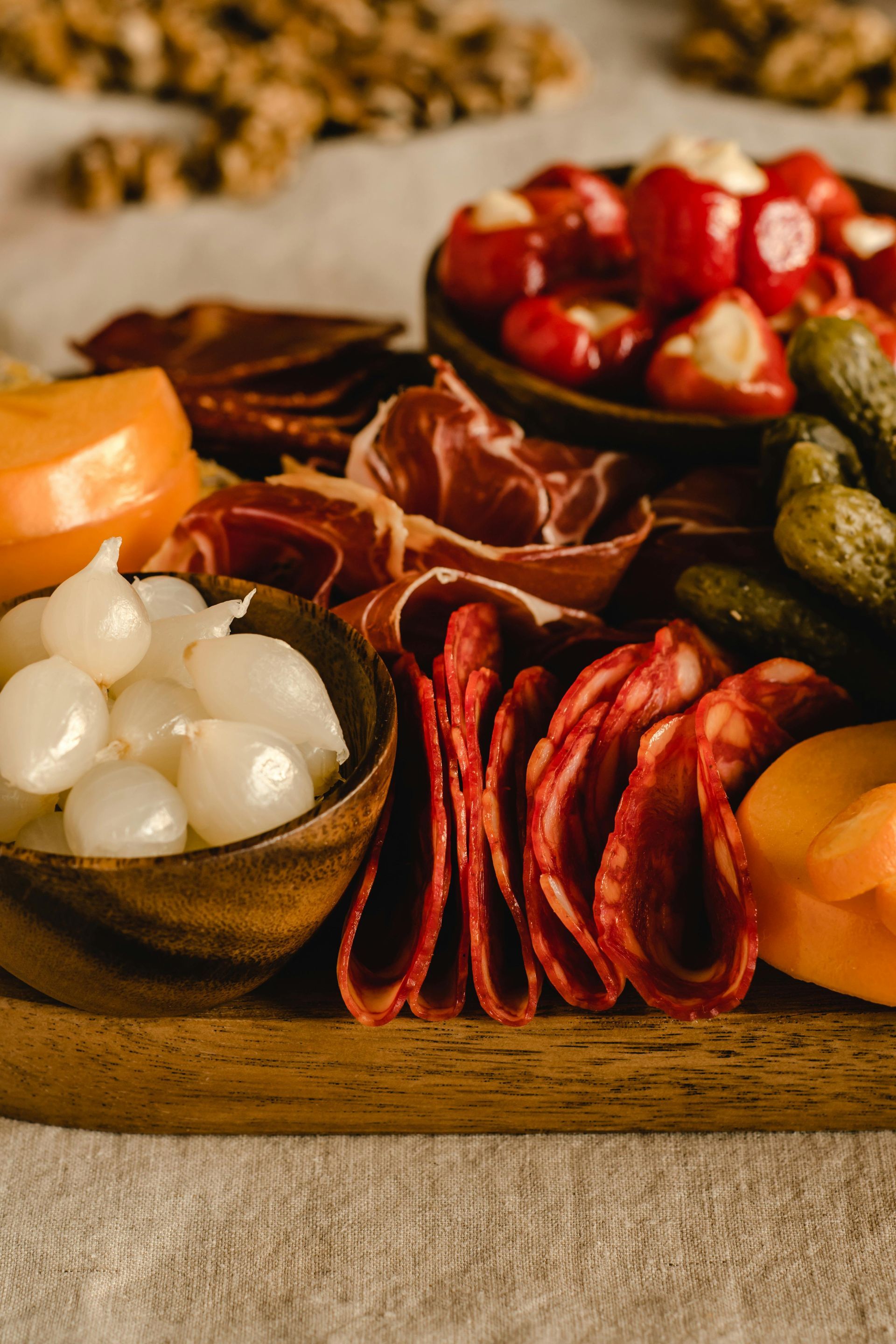 Charcuterie board with cured meats, cheese, pickled vegetables, and peppers.