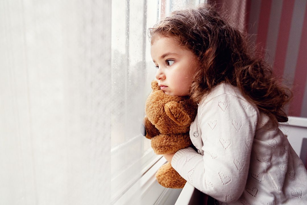 Children & Grief, Child looking out window holding teddy bear
