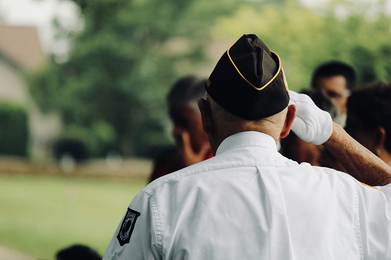a man in a military uniform salutes in front of a crowd