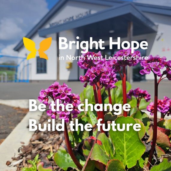 Woman smiles at an elderly person seated in a chair, a walker nearby.