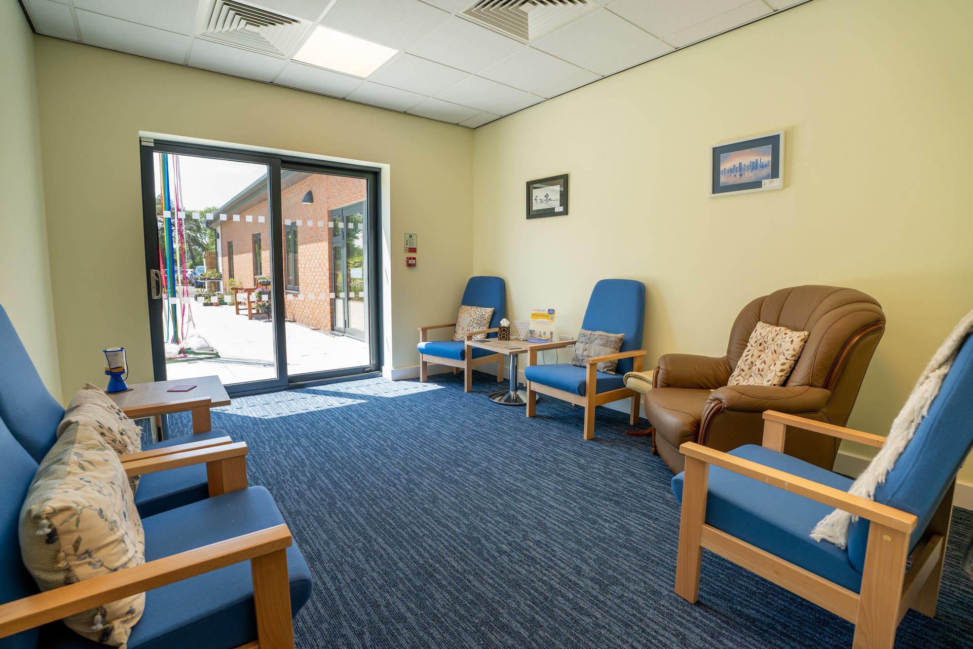 Bright room with blue armchairs, a brown armchair, and a doorway to an outdoor patio.