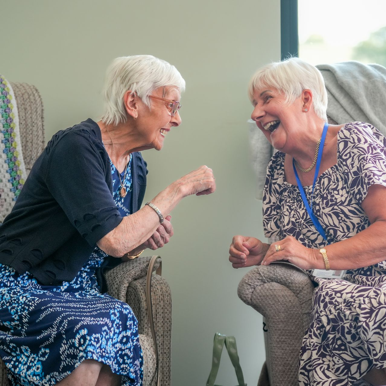 Hands stacked together, wearing colorful sweaters, demonstrating teamwork.