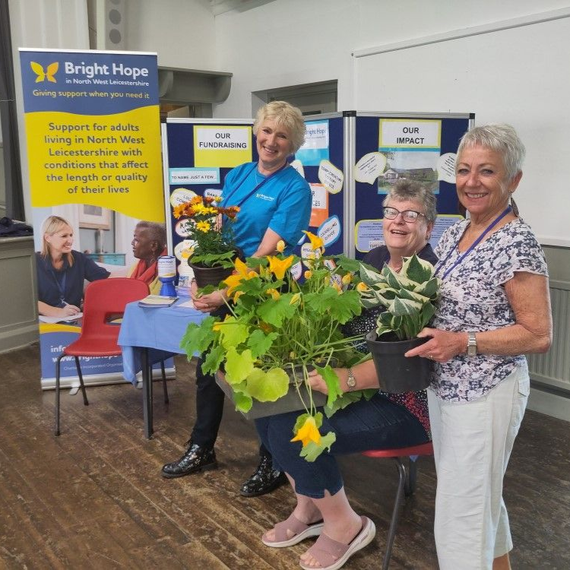Woman smiles at an elderly person seated in a chair, a walker nearby.