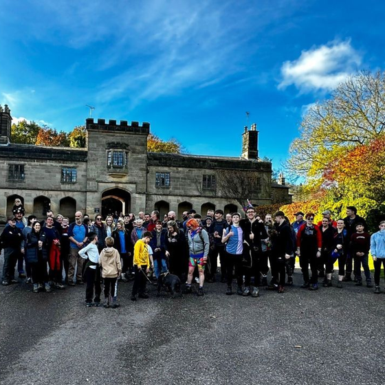 Woman smiles at an elderly person seated in a chair, a walker nearby.
