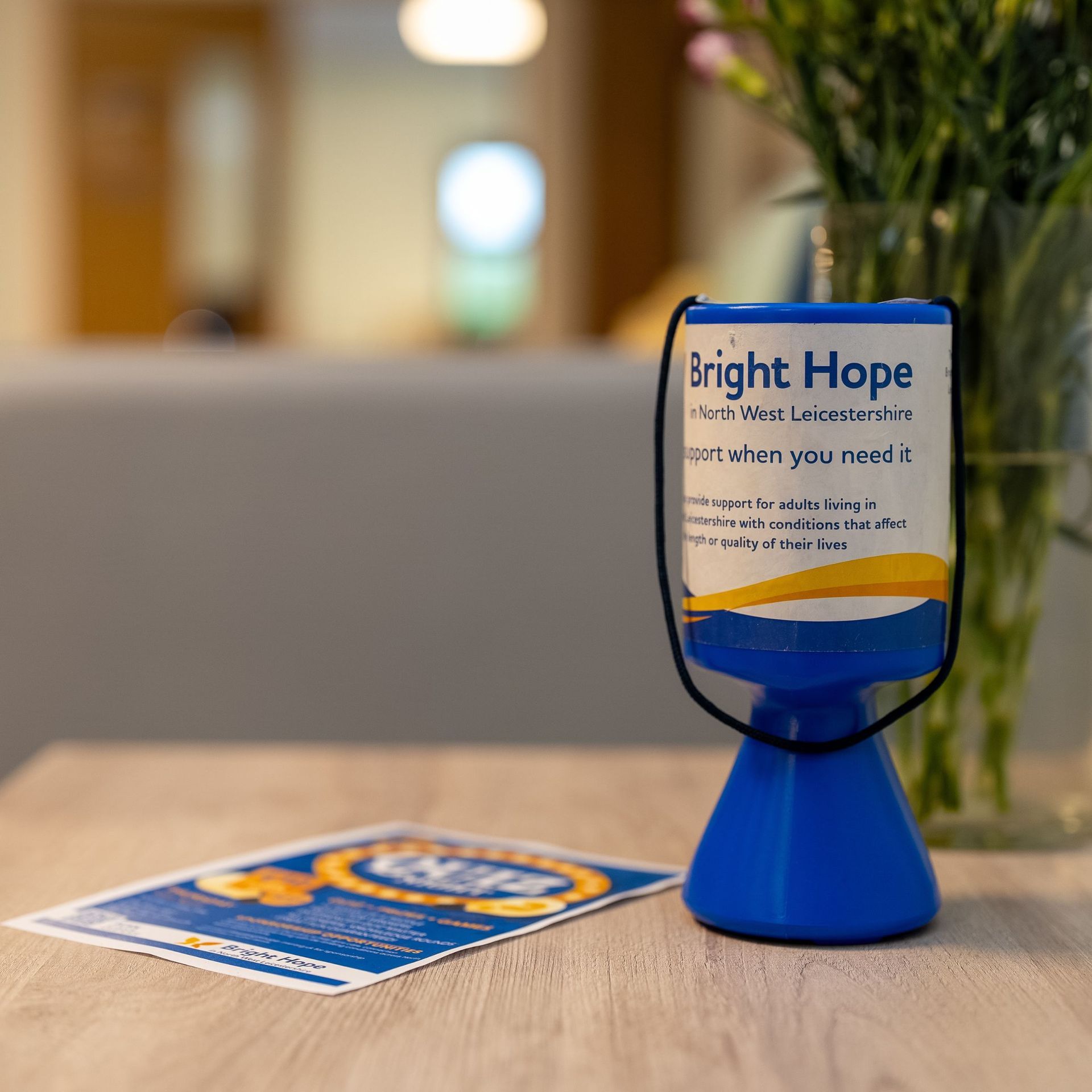 Woman smiles at an elderly person seated in a chair, a walker nearby.