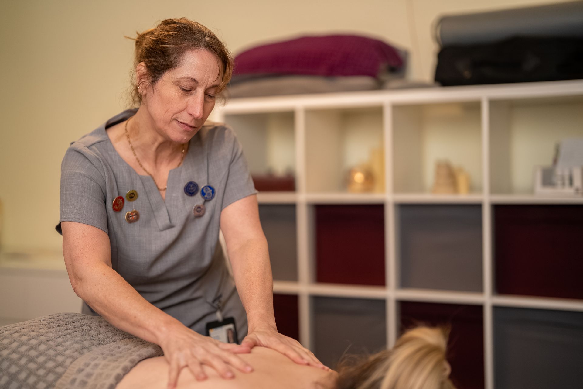 Hands massaging a person's shoulder and upper back. Focus on the hands and body.