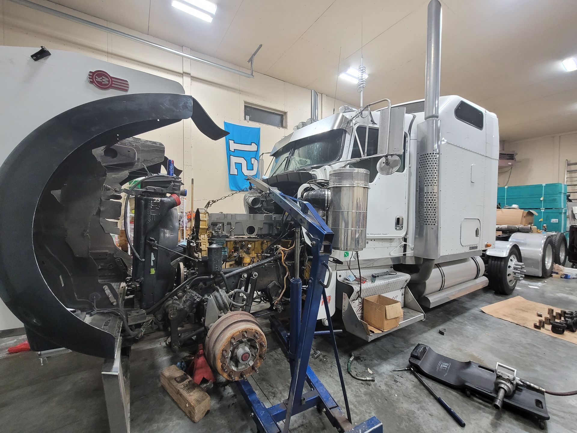 A semi truck is being repaired in a garage.