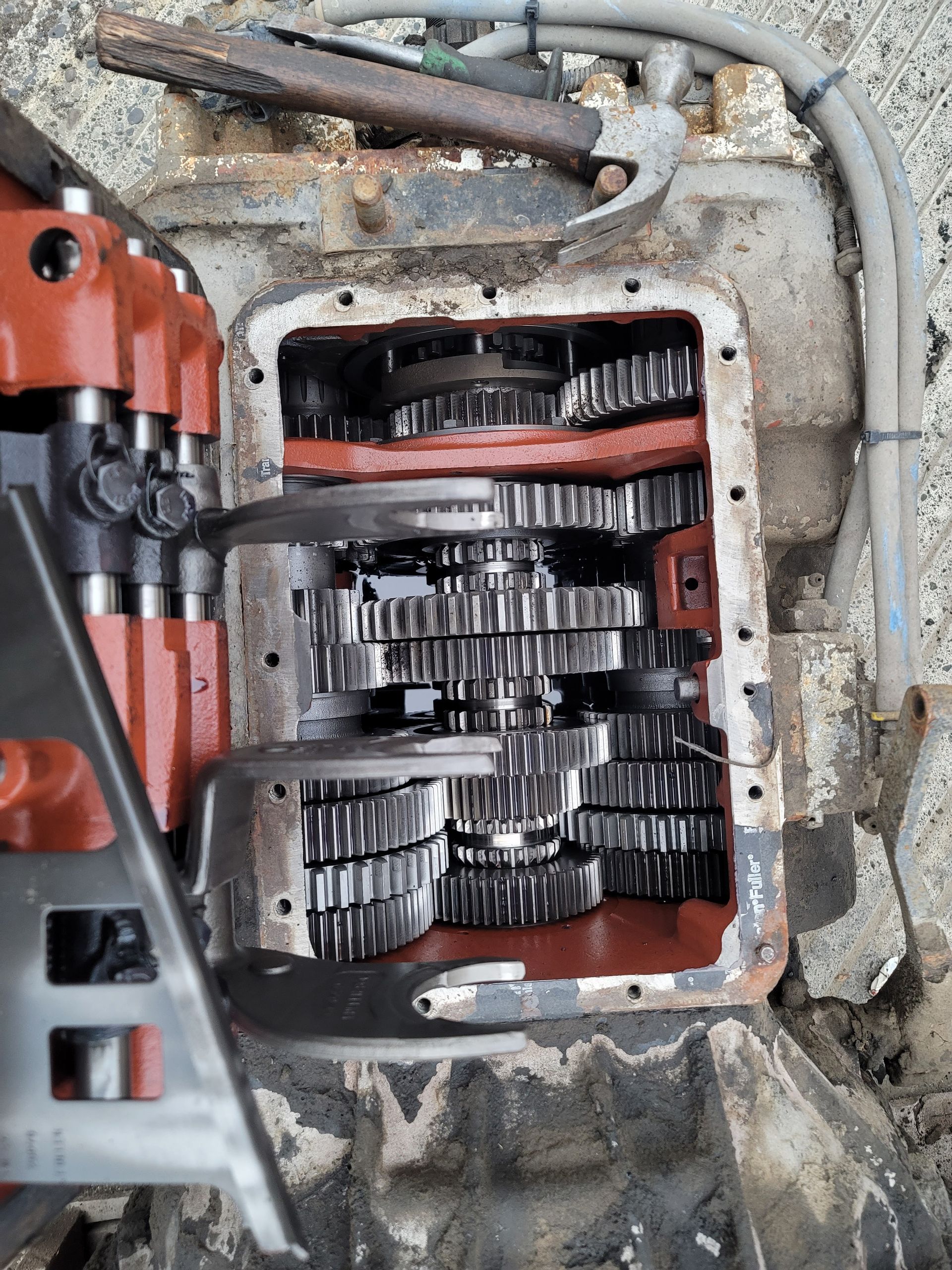 The inside of a gearbox is shown with a hammer in the background.