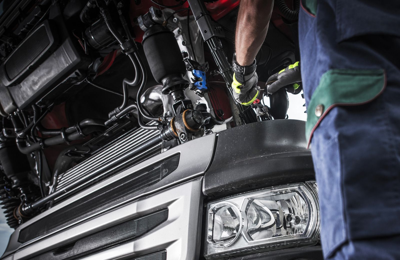A man is working on the engine of a truck.