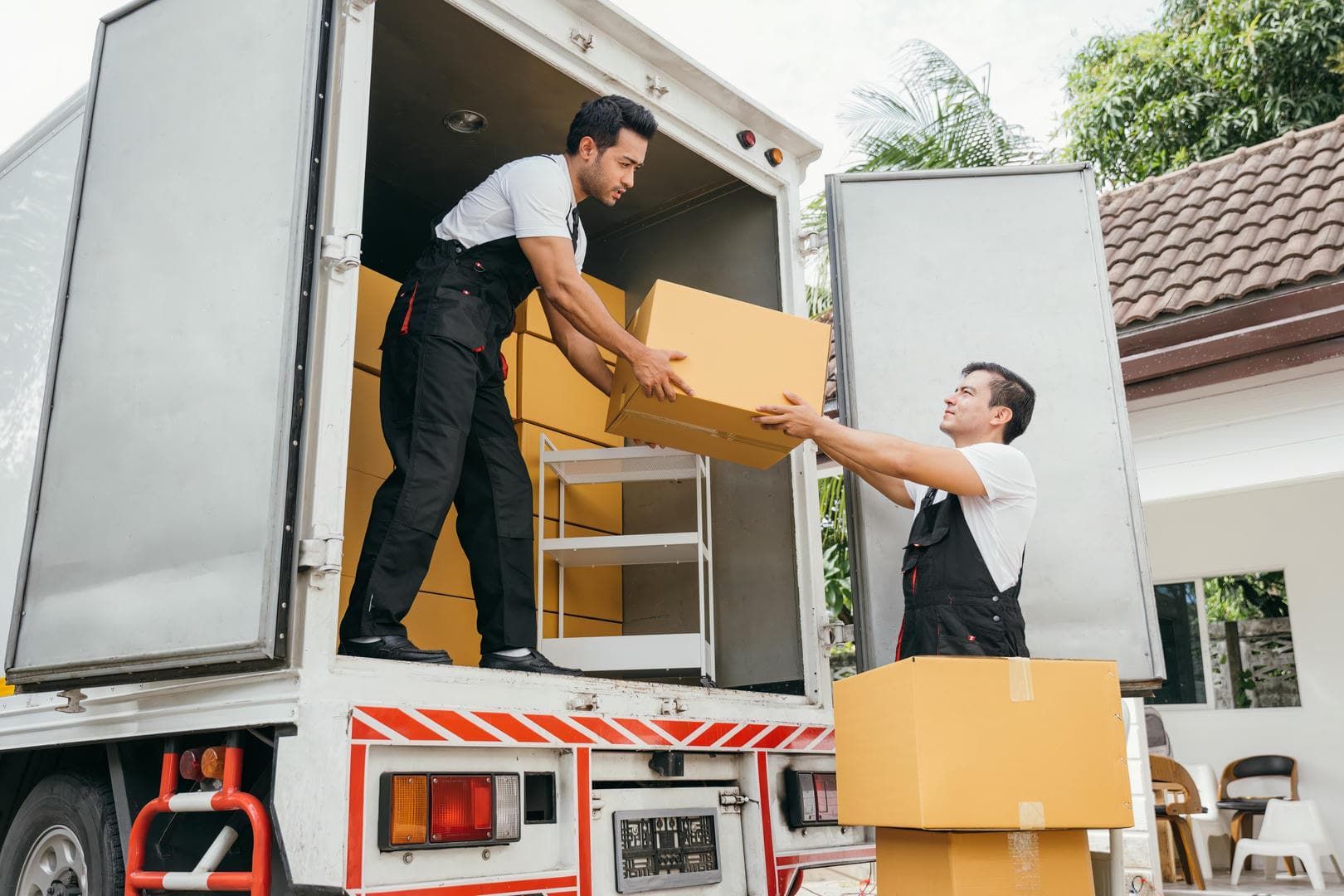Two men are loading boxes into a moving truck.