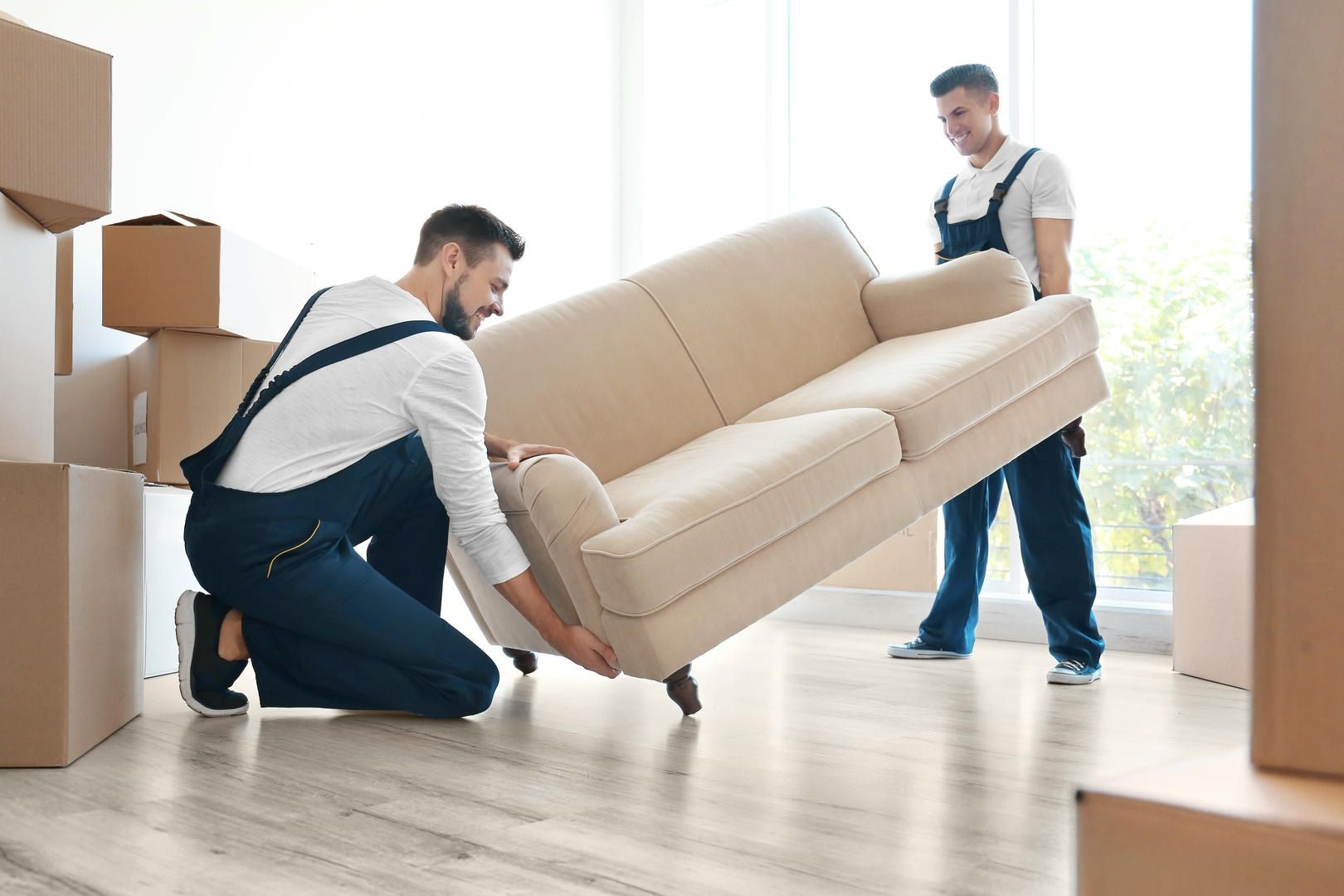 Two men are moving a couch in a living room.