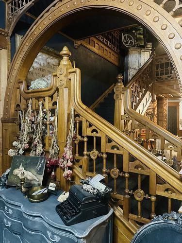 Ornate wooden staircase with detailed carvings and vintage desk.