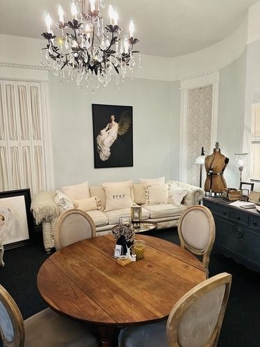 A room with a round wooden table and chairs, a couch, and a chandelier.