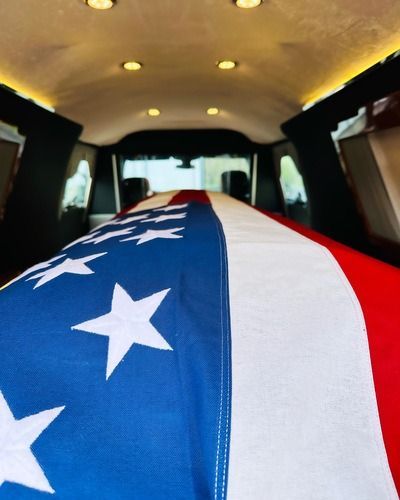 Coffin draped with American flag inside a hearse.