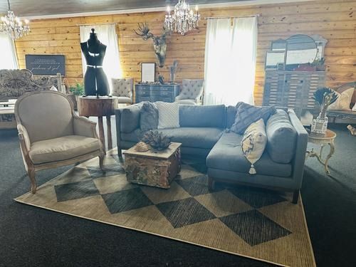 Living room with a sectional sofa, a rug, a wooden side table, and a mannequin.