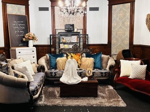 Cozy living room with multiple sofas, pillows, and decorative items. Warm tones and chandelier.