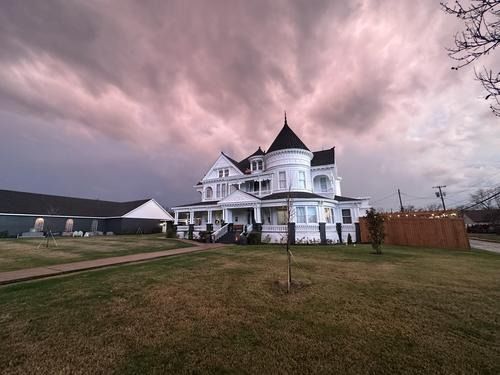 White Victorian house with a dark, cloudy sky overhead.