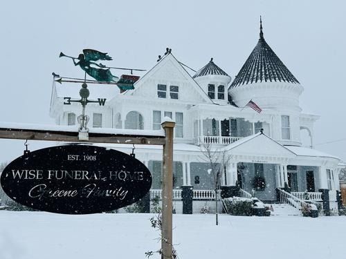 White Wise Funeral Home in snow with sign; angel weather vane.