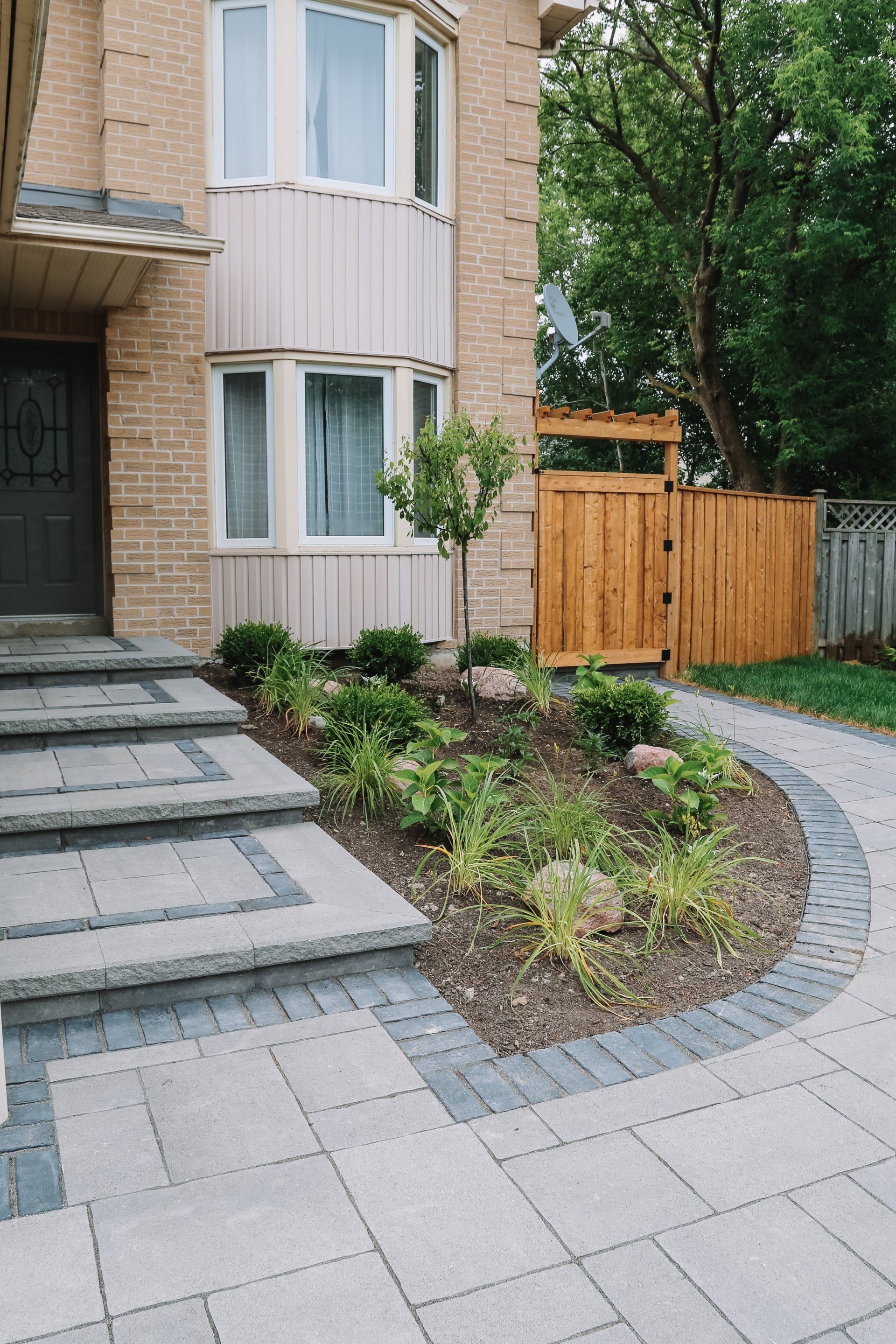 A house with a brick walkway leading to the front door and a wooden gate.