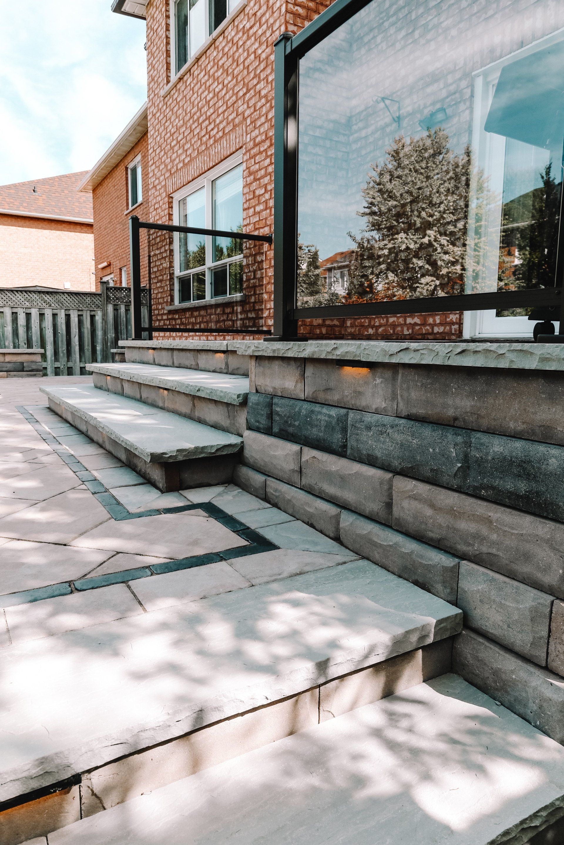 A brick wall with stairs leading up to a patio in front of a house.
