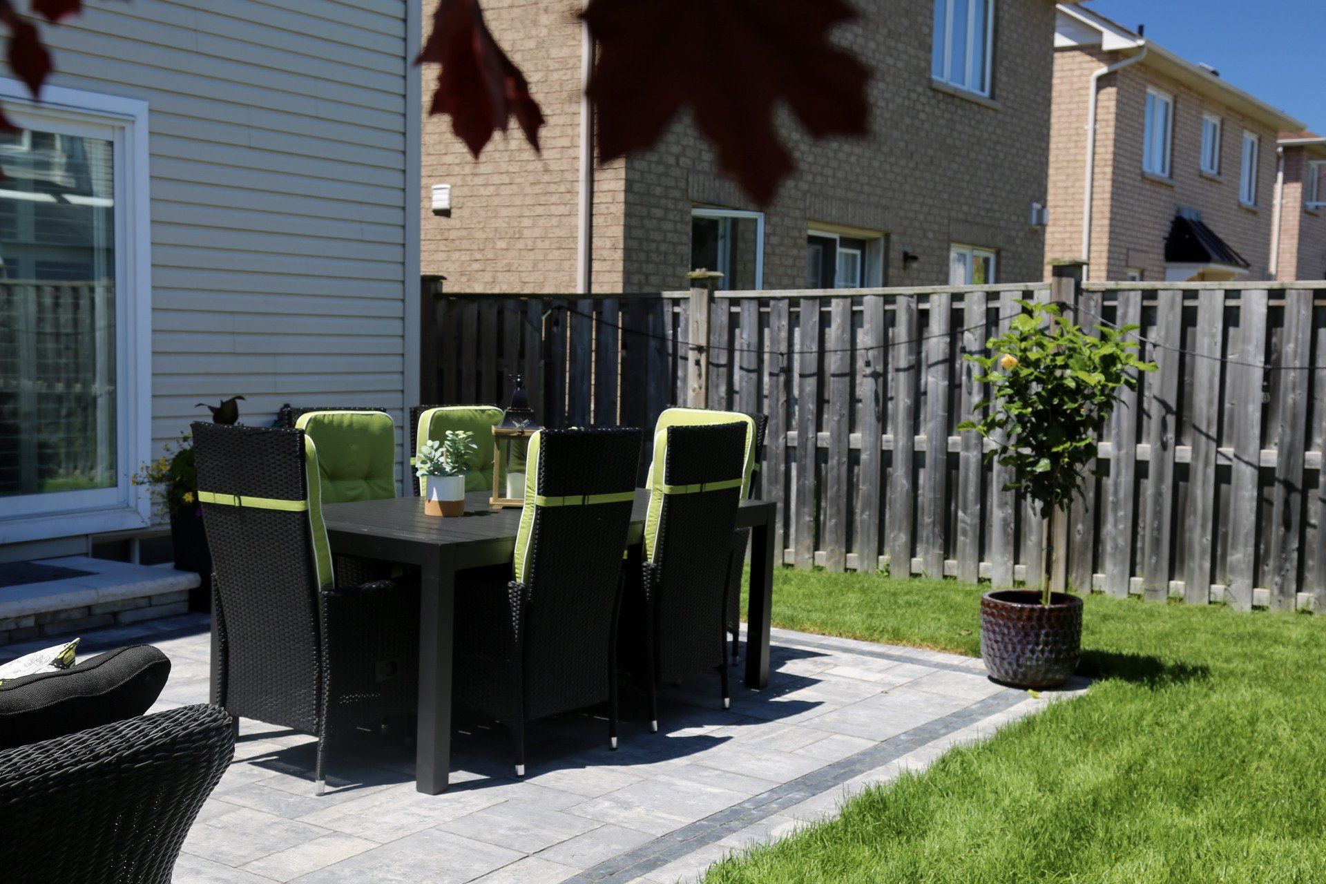 A patio with a table and chairs in the backyard of a house.