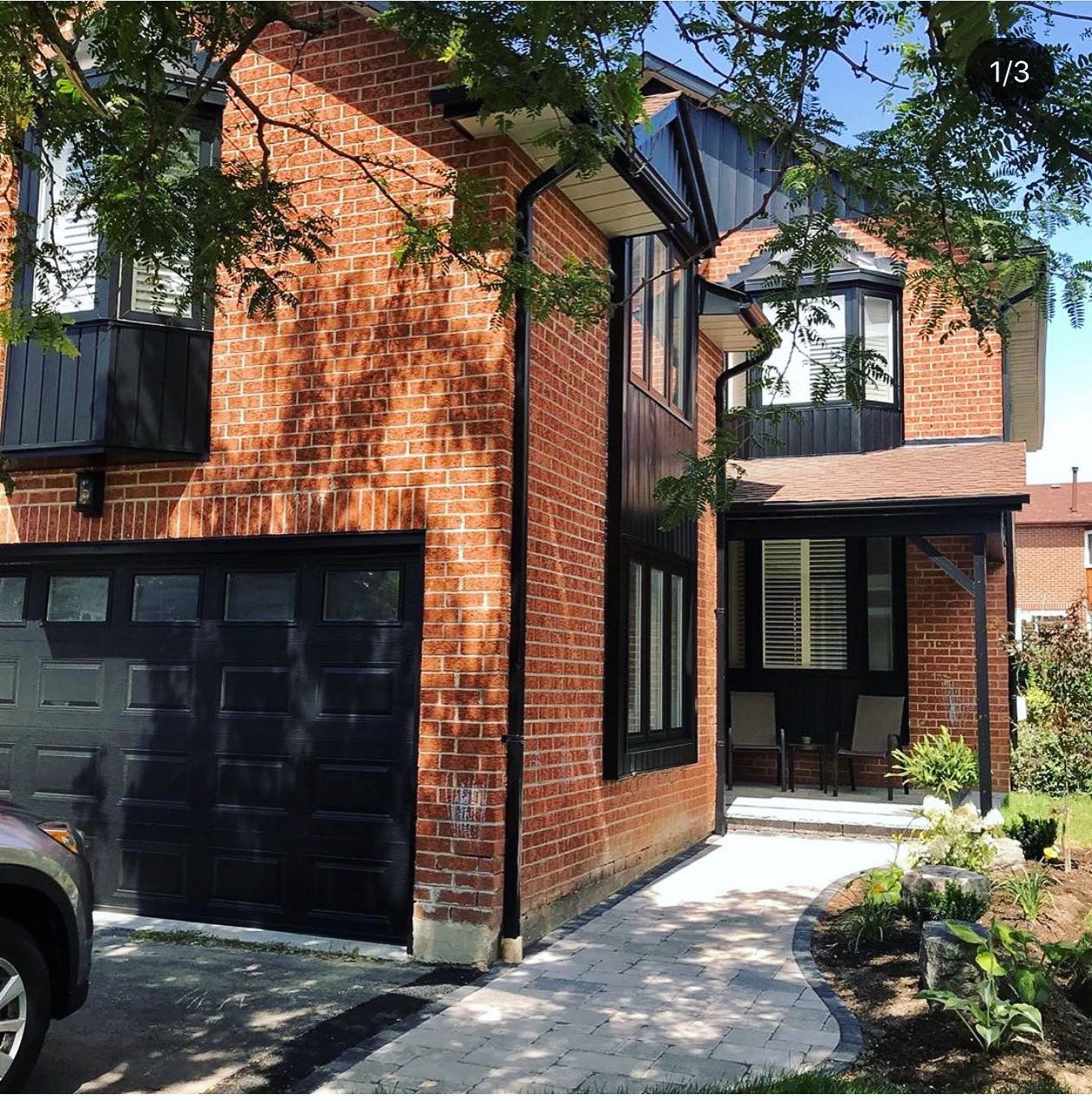 A brick house with a black garage door and a car parked in front of it