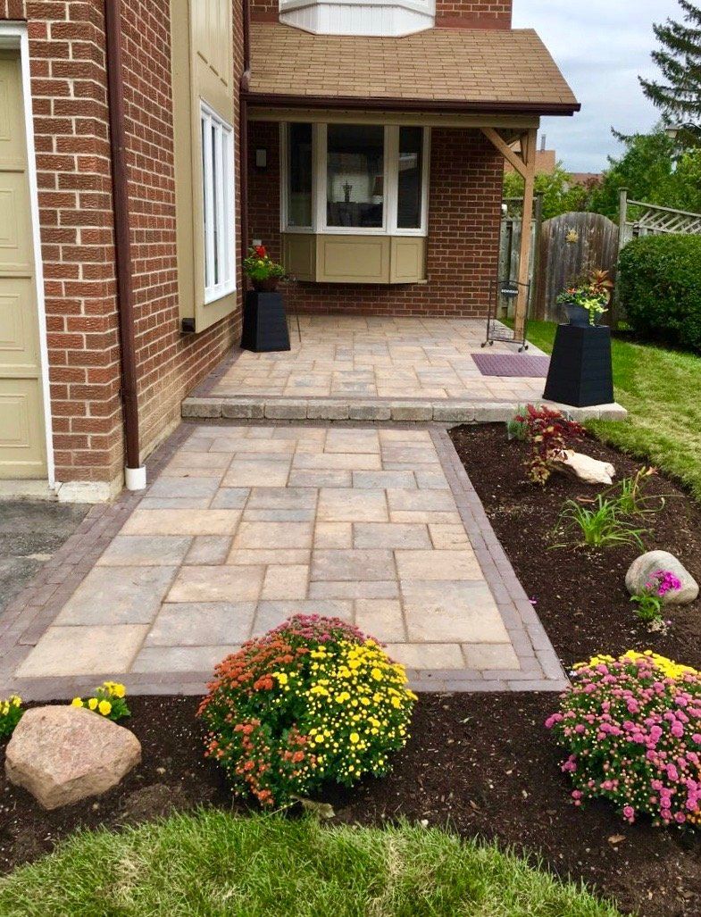 A brick house with a patio and flowers in front of it.