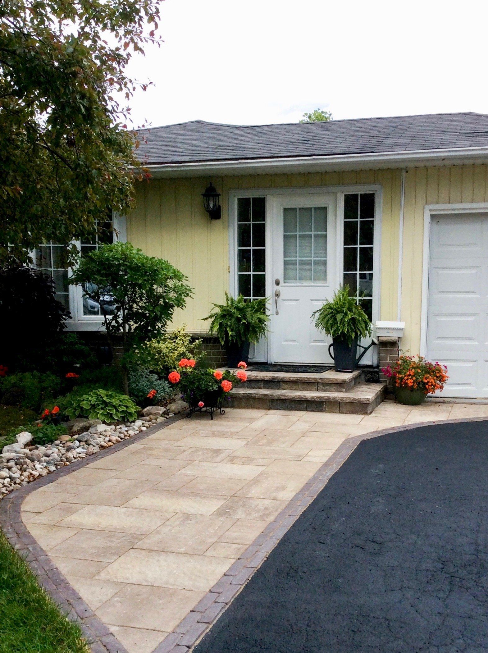 A yellow house with a white door and a black driveway